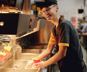 Młody pracownik McDonald's przy stacji z frytkami