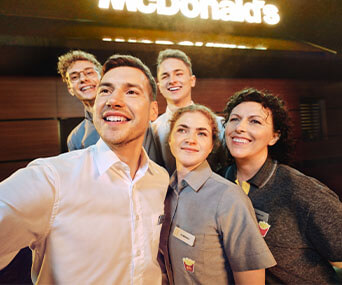 5 pracowników robiących sobie selfie na tle restauracji McDonald's