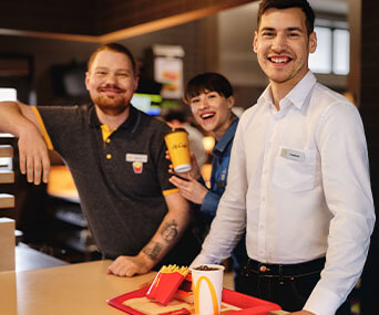 Trzech uśmiechniętych pracowników restauracji McDonald's